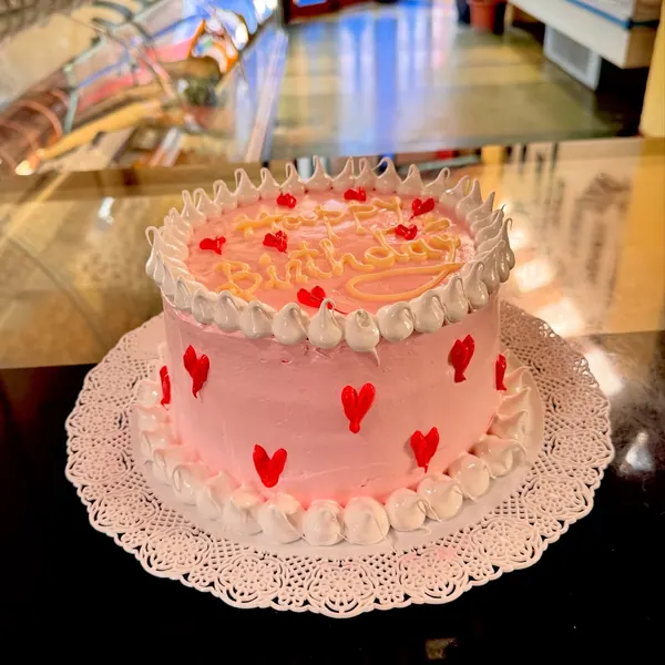 Torta rosada con corazones rojos sobre una blonda